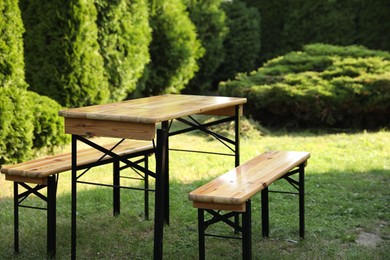 Photo of Wooden table with benches in garden on sunny day