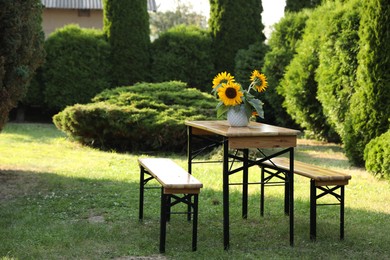 Vase with sunflowers on wooden table in garden