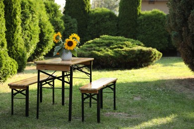 Vase with sunflowers on wooden table in garden