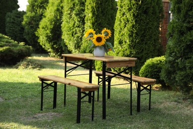 Photo of Vase with sunflowers on wooden table in garden