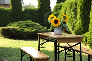 Photo of Vase with sunflowers on wooden table in garden