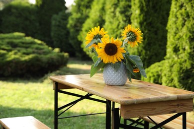 Photo of Vase with sunflowers on wooden table in garden