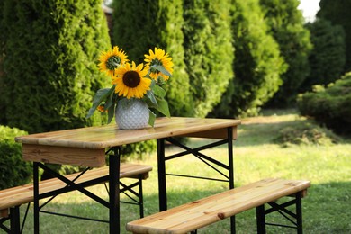 Photo of Vase with sunflowers on wooden table in garden