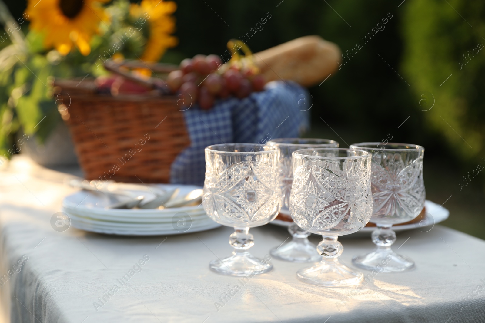 Photo of Glasses, plates, fresh products and sunflowers on table in garden, closeup