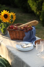 Plates, fresh products and sunflowers on table in garden