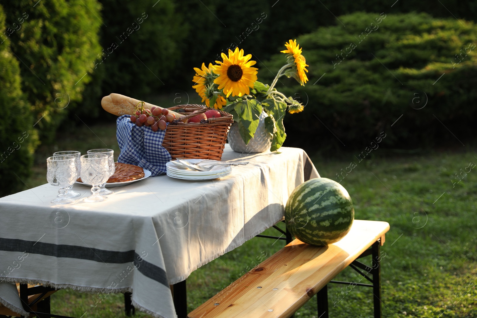 Photo of Glasses, plates, fresh products and sunflowers on table in garden