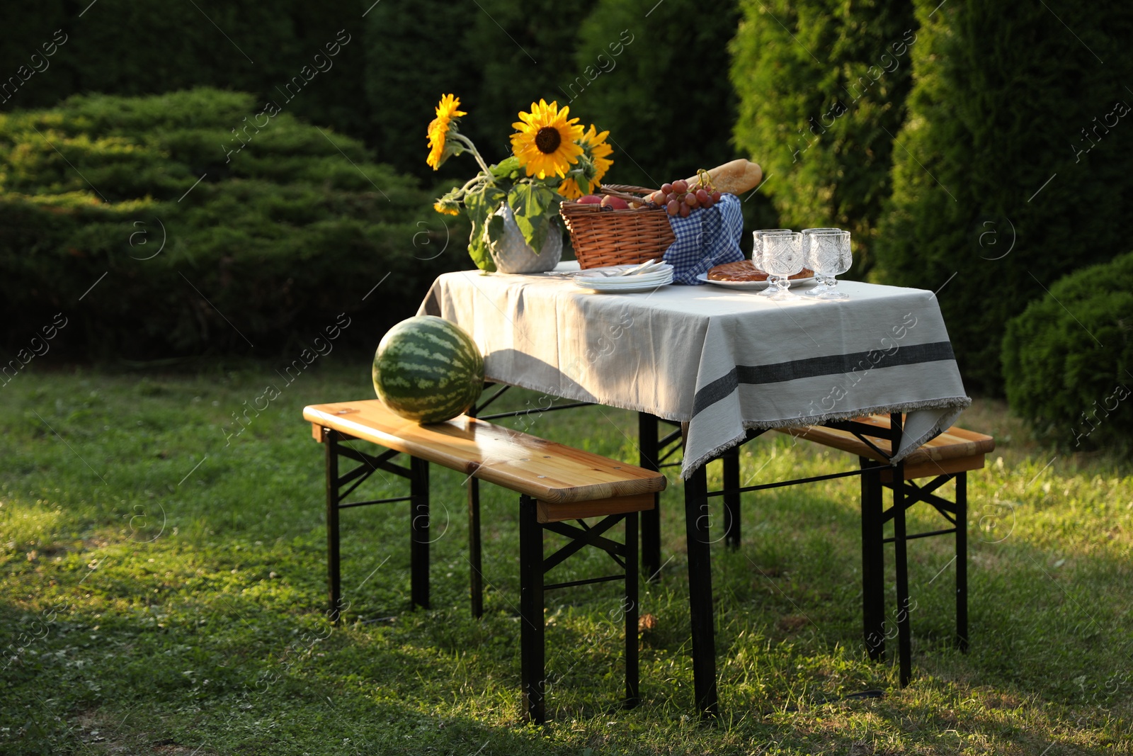 Photo of Glasses, plates, fresh products and sunflowers on table in garden