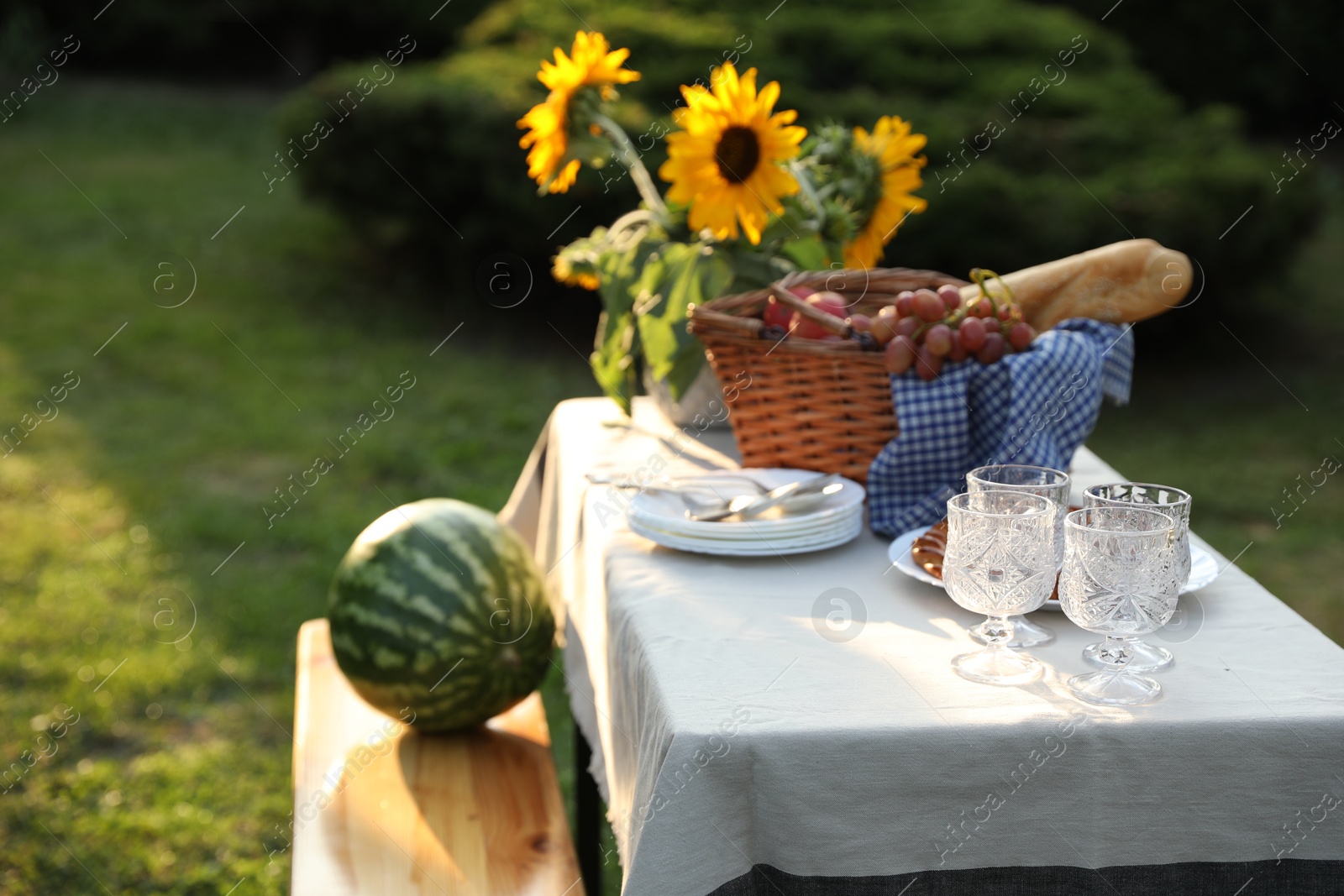 Photo of Glasses, plates, fresh products and sunflowers on table in garden