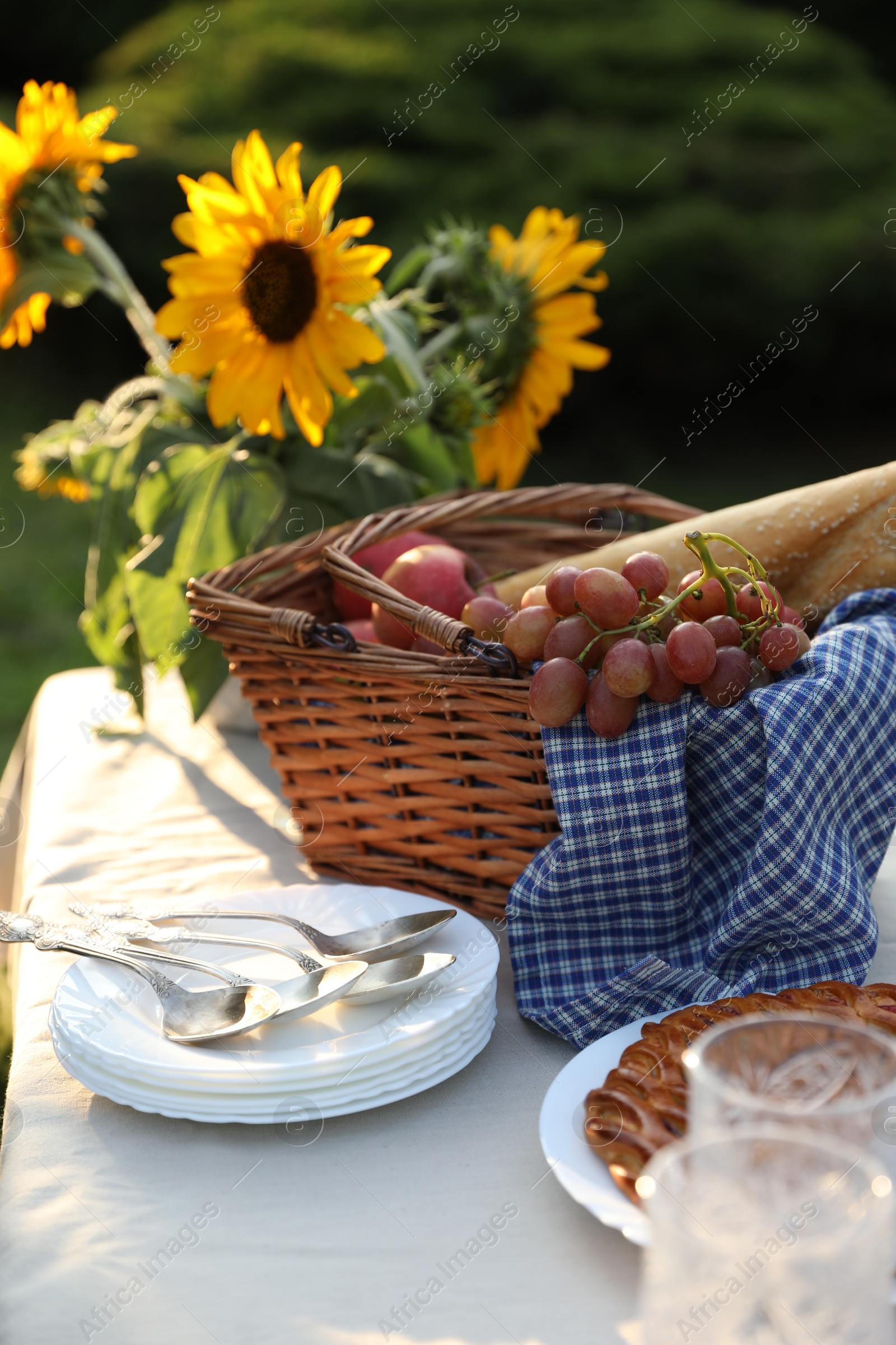 Photo of Plates, fresh products and sunflowers on table in garden