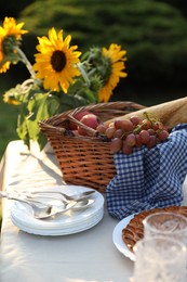 Plates, fresh products and sunflowers on table in garden