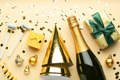 Photo of Flat lay composition with confetti and bottle of sparkling wine on beige background. Christmas decor