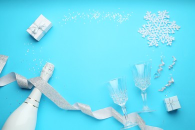 Photo of Flat lay composition with confetti and bottle of sparkling wine on light blue background, space for text. Christmas decor