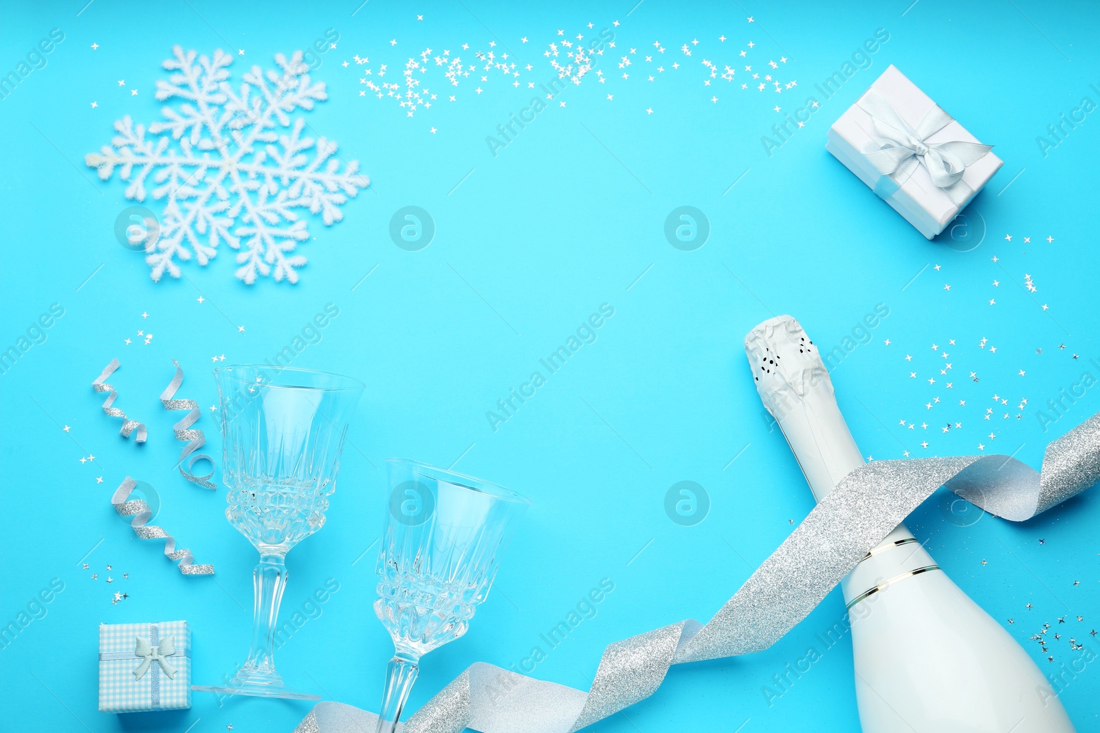 Photo of Flat lay composition with confetti and bottle of sparkling wine on light blue background, space for text. Christmas decor