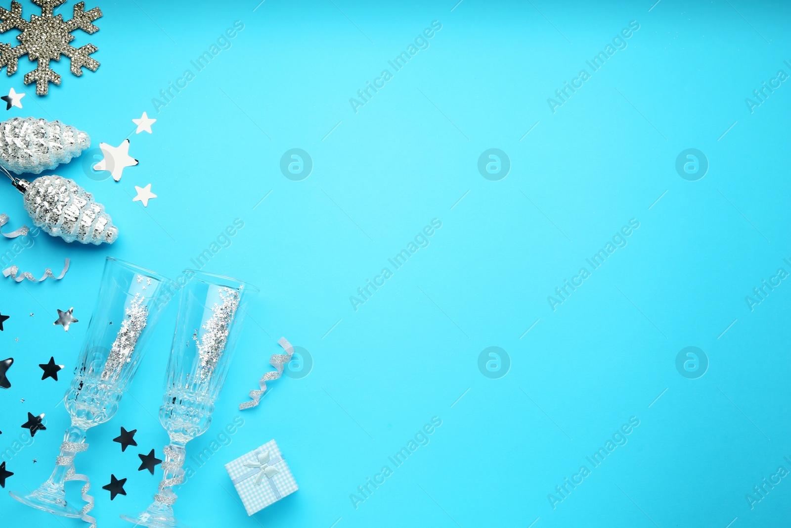 Photo of Flat lay composition with confetti and other Christmas decor on light blue background, space for text