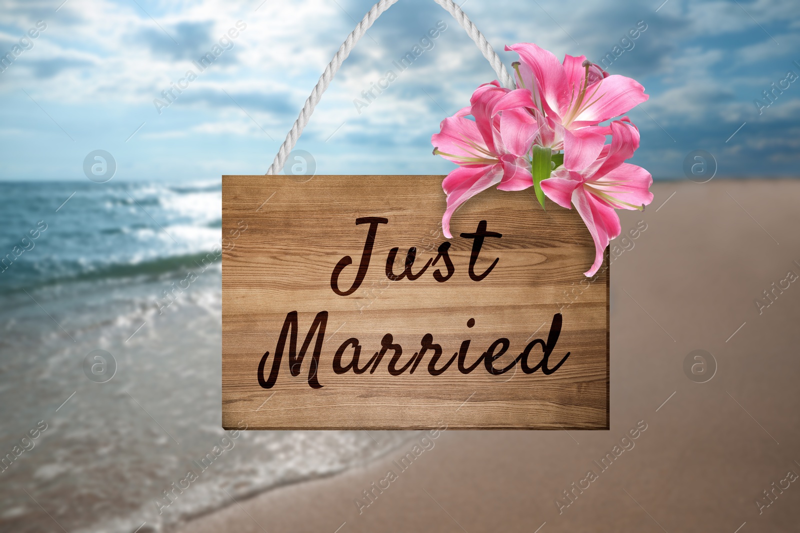 Image of Honeymoon. Wooden board with words Just Married and flowers on sandy seashore