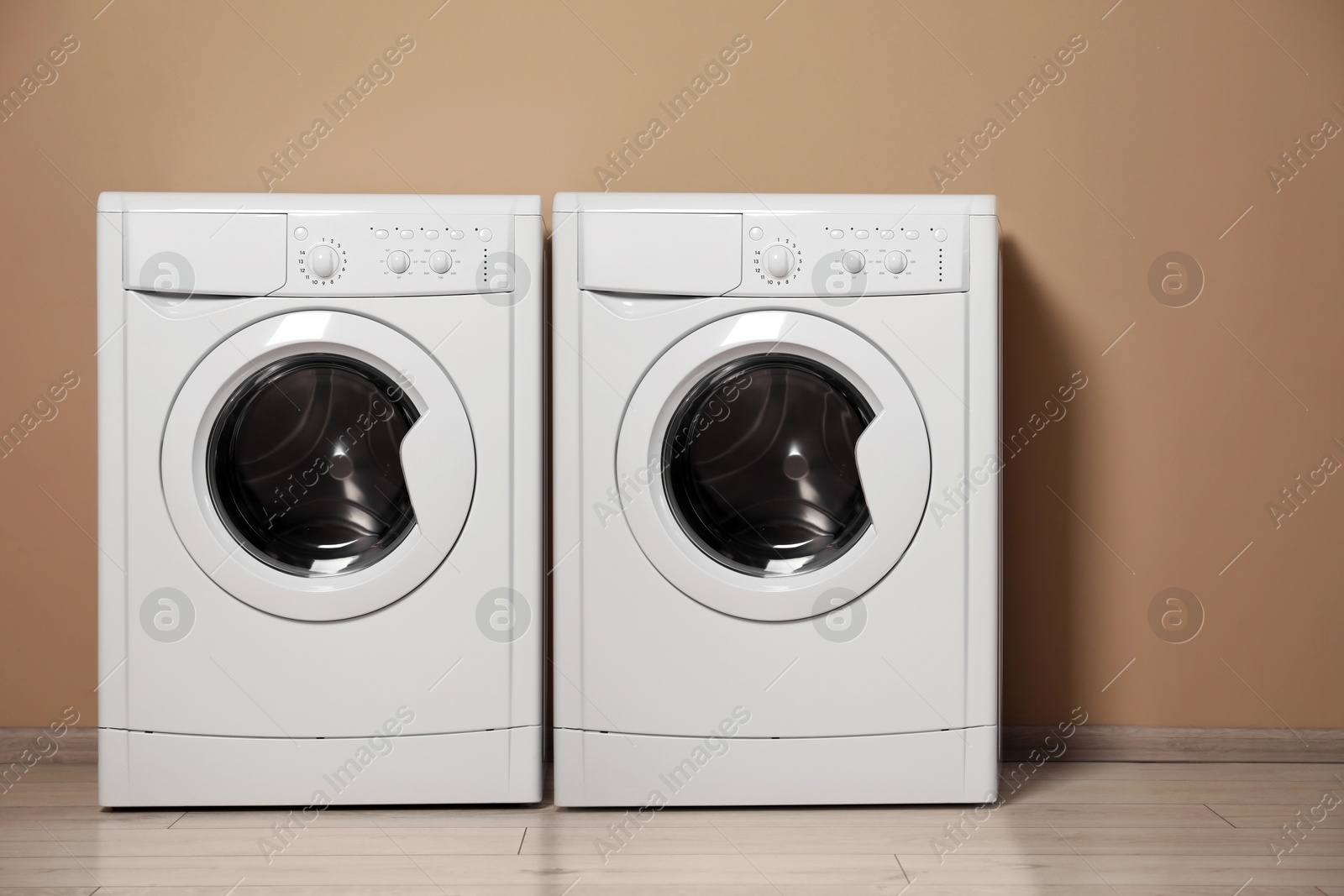 Image of Two washing machines near dark beige wall