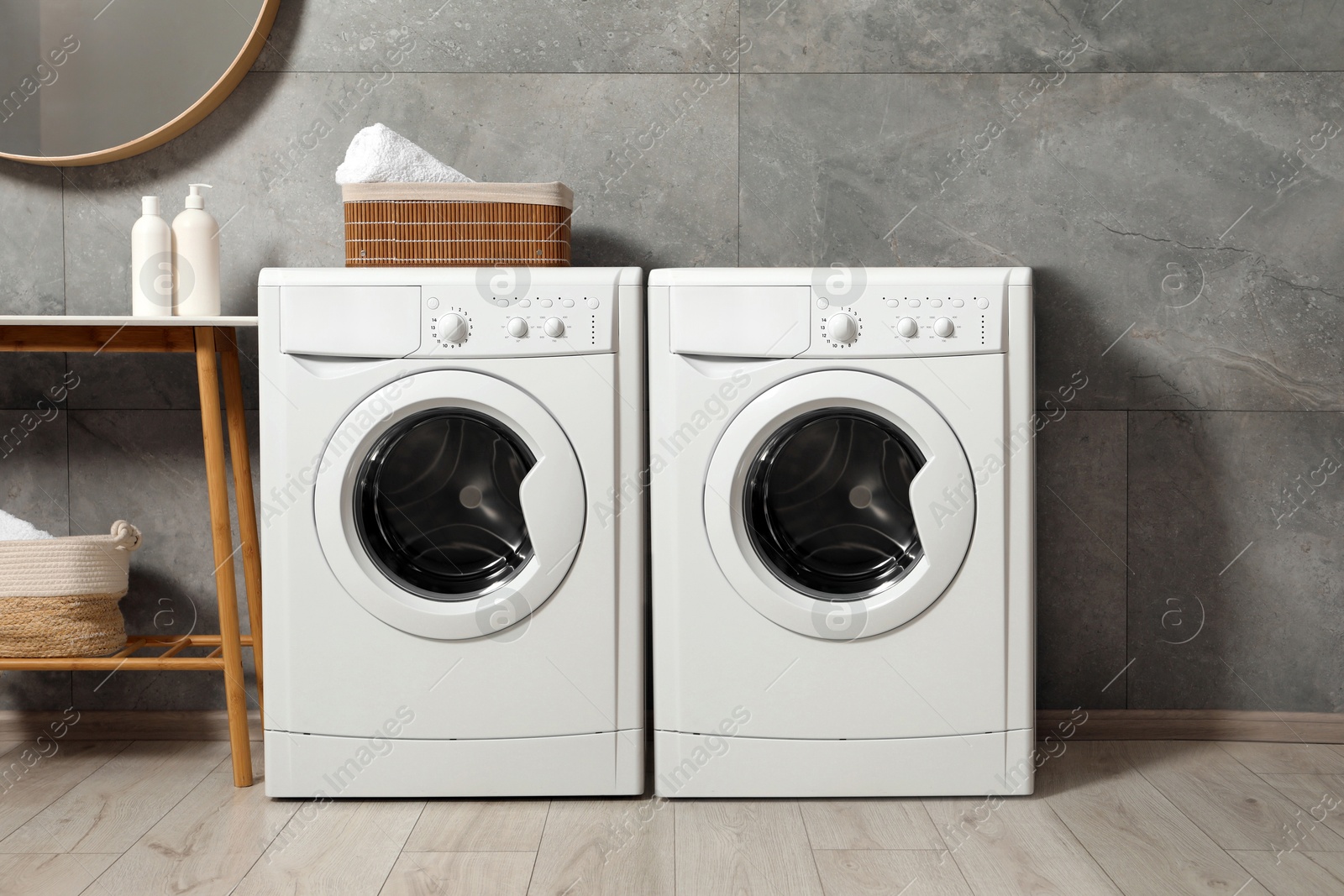 Image of Two washing machines near grey tiled wall in laundry room