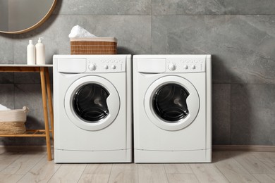 Image of Two washing machines near grey tiled wall in laundry room