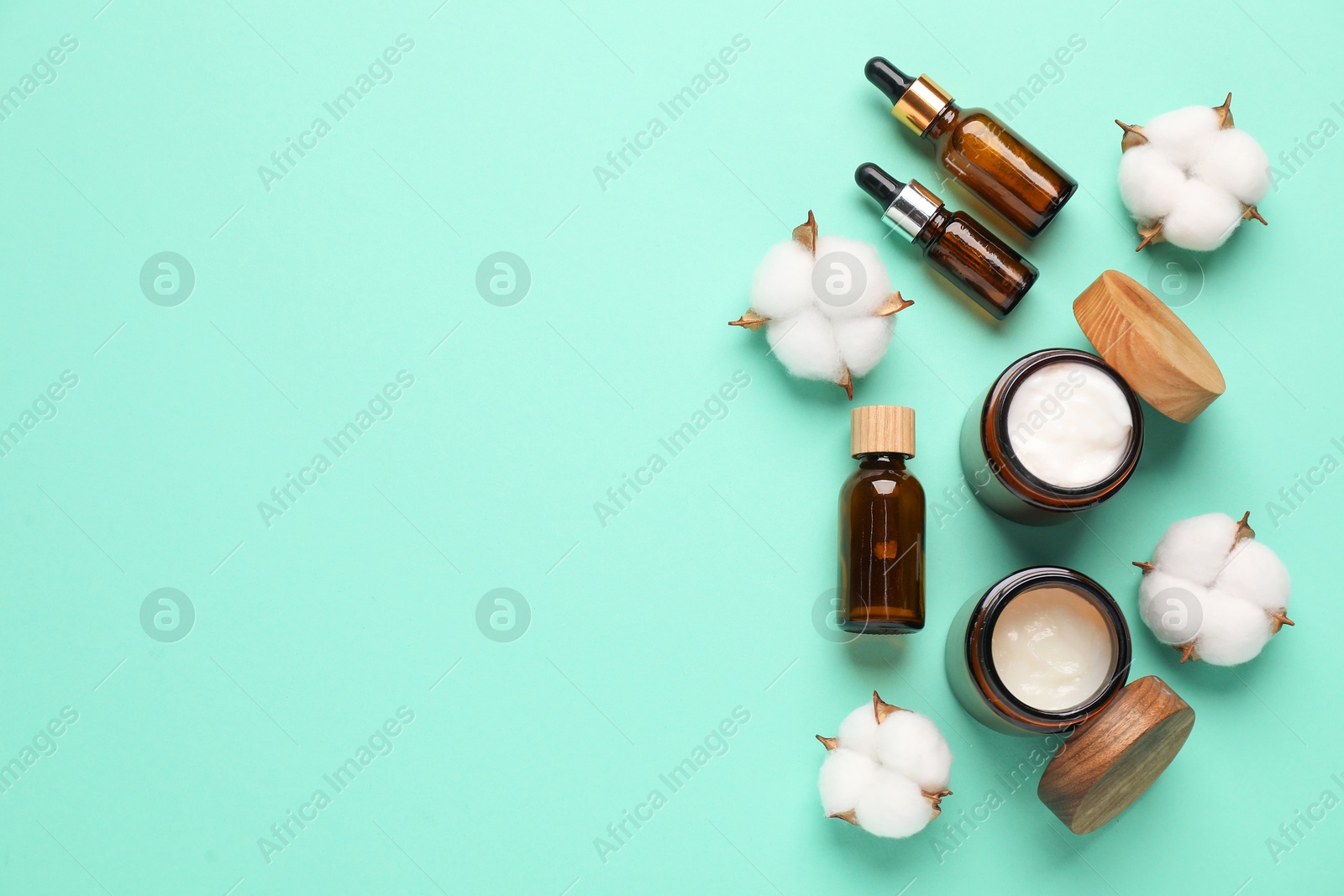 Photo of Different cosmetic products and cotton flowers on turquoise background, flat lay. Space for text