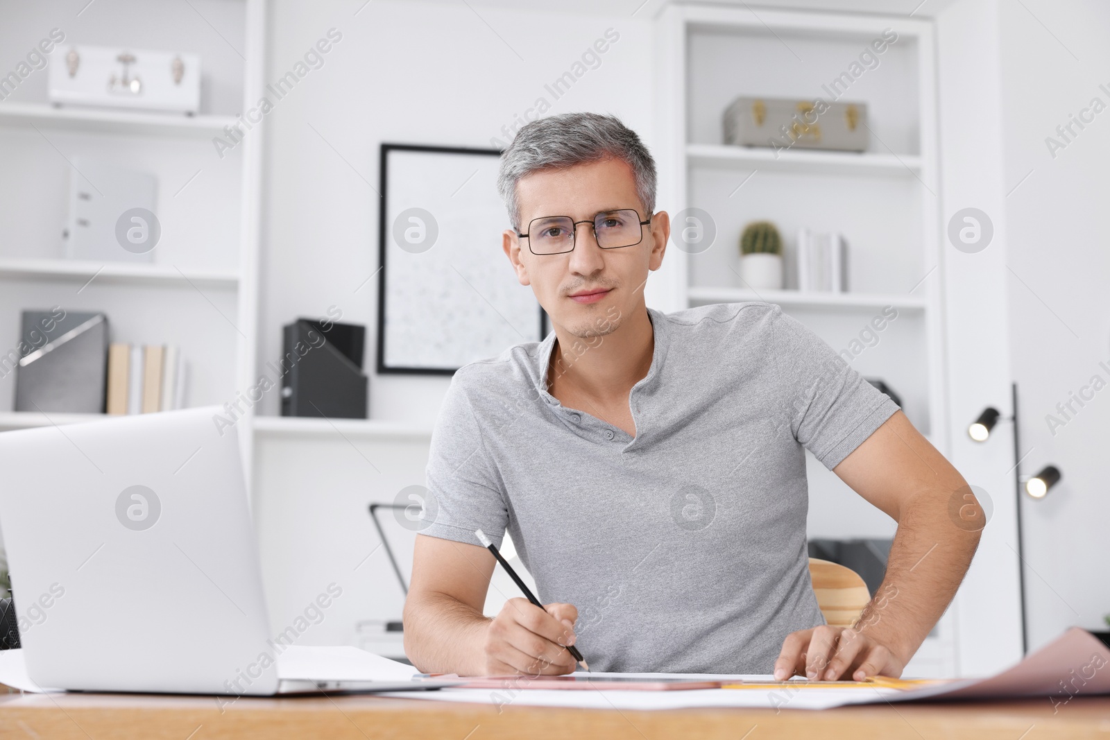 Photo of Architect with engineering drawing at wooden table in office