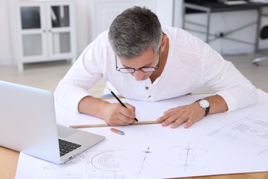 Photo of Architect making engineering drawing at wooden table in office