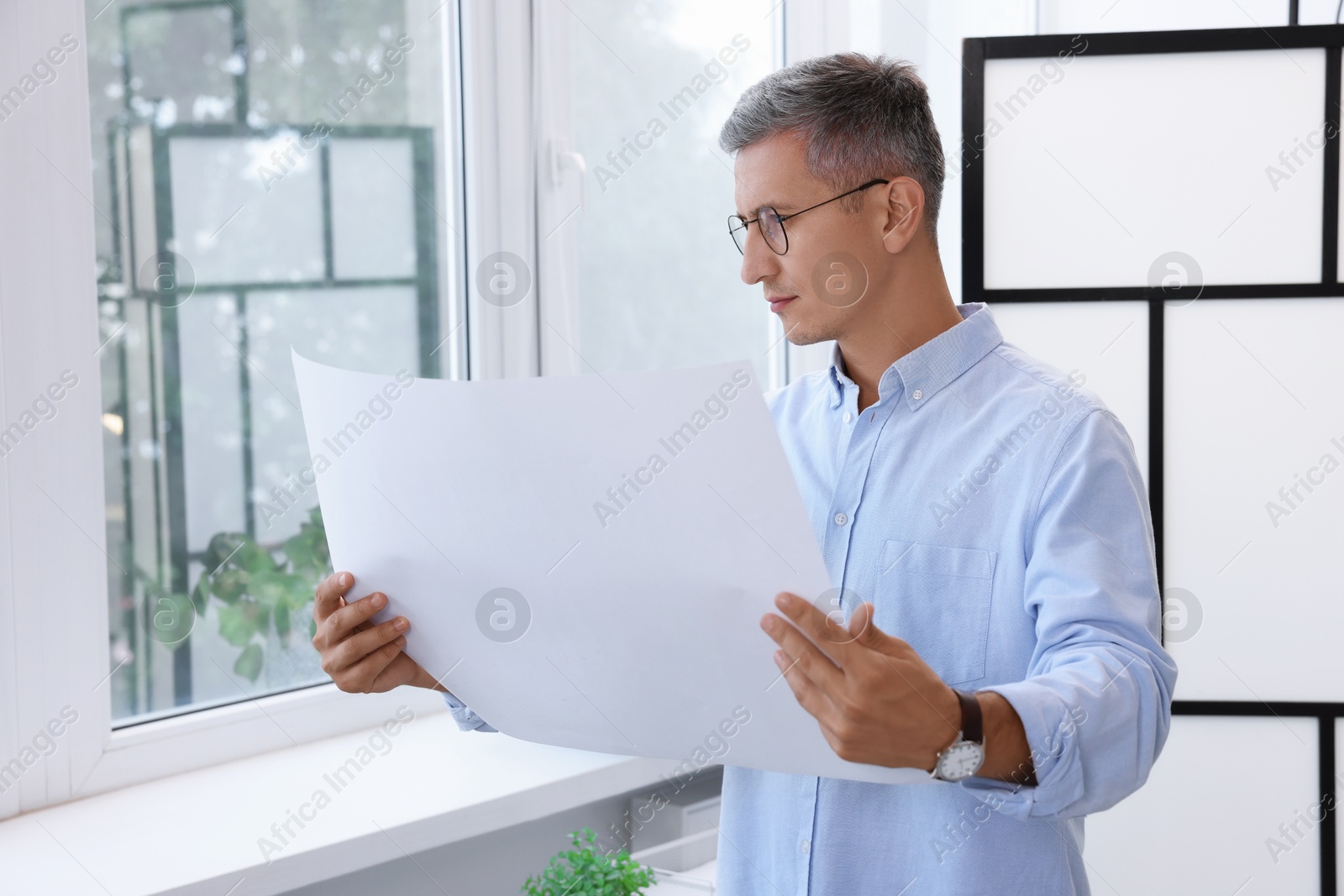 Photo of Architect holding paper sheet with engineering drawing in office