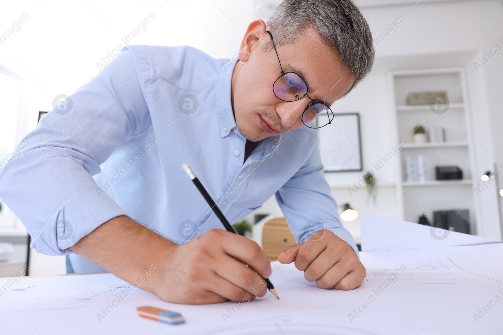 Photo of Architect making engineering drawing at table in office, low angle view