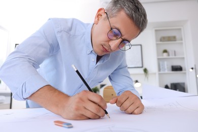 Architect making engineering drawing at table in office, low angle view