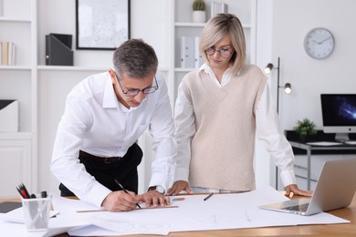 Architects making engineering drawing at wooden table in office