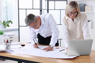 Architects making engineering drawing at wooden table in office