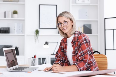 Architect making engineering drawing at table in office