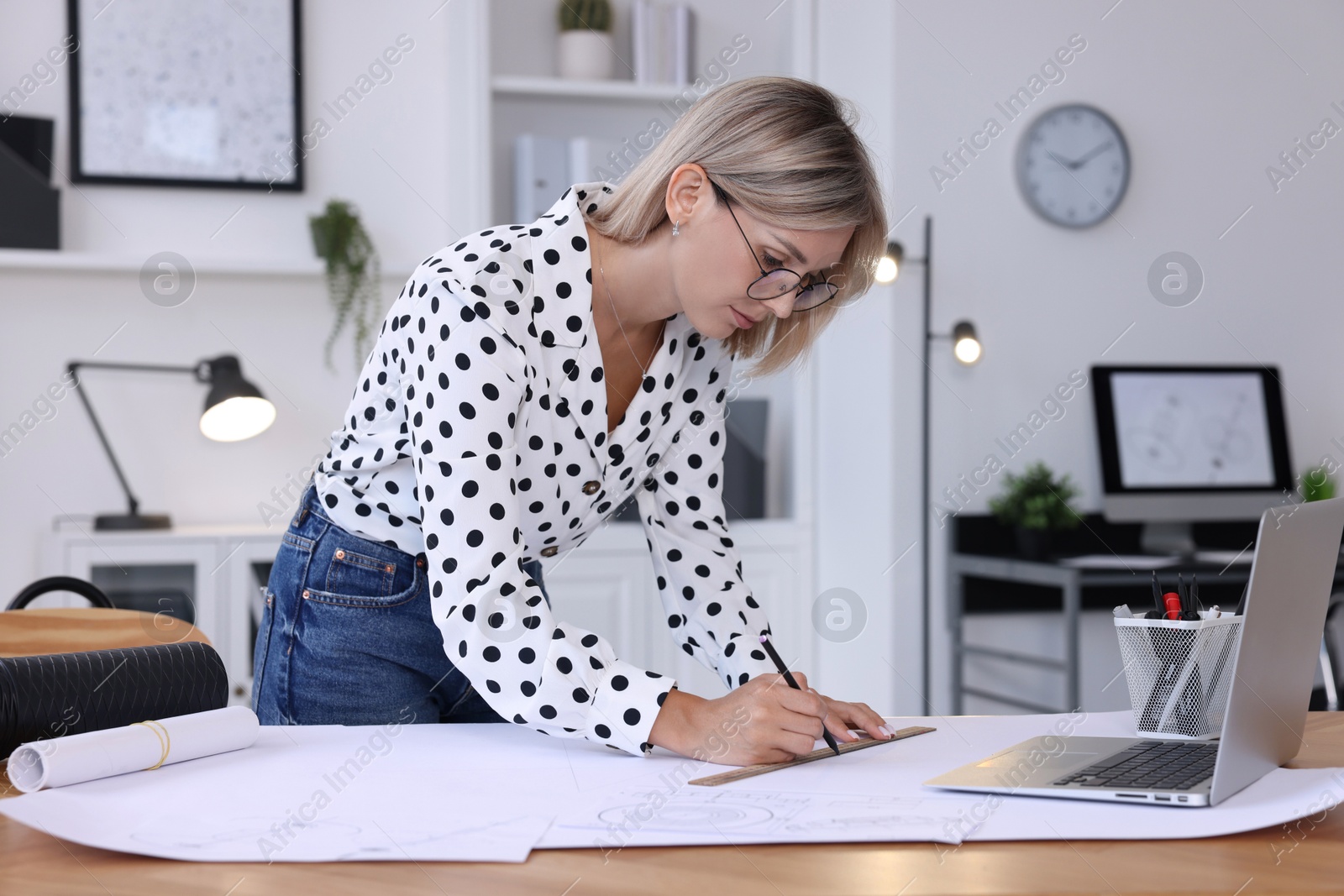 Photo of Architect making engineering drawing at wooden table in office