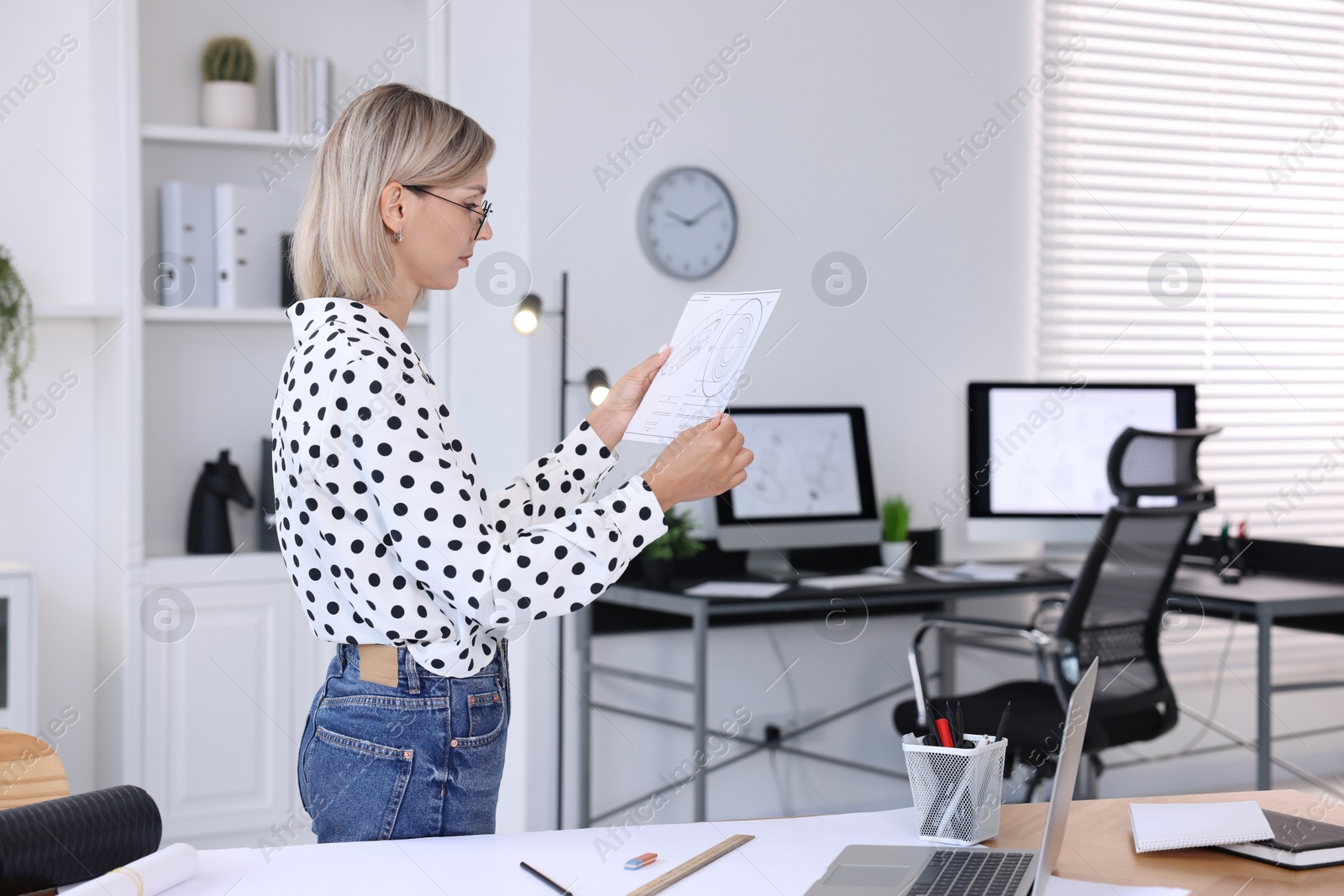 Photo of Architect holding paper sheet with engineering drawing in office