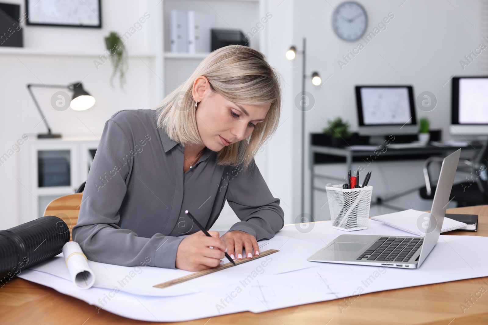 Photo of Architect making engineering drawing at wooden table in office