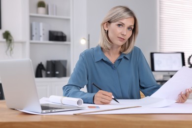 Architect making engineering drawing at table in office