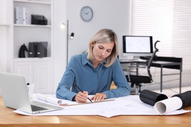 Architect making engineering drawing at wooden table in office