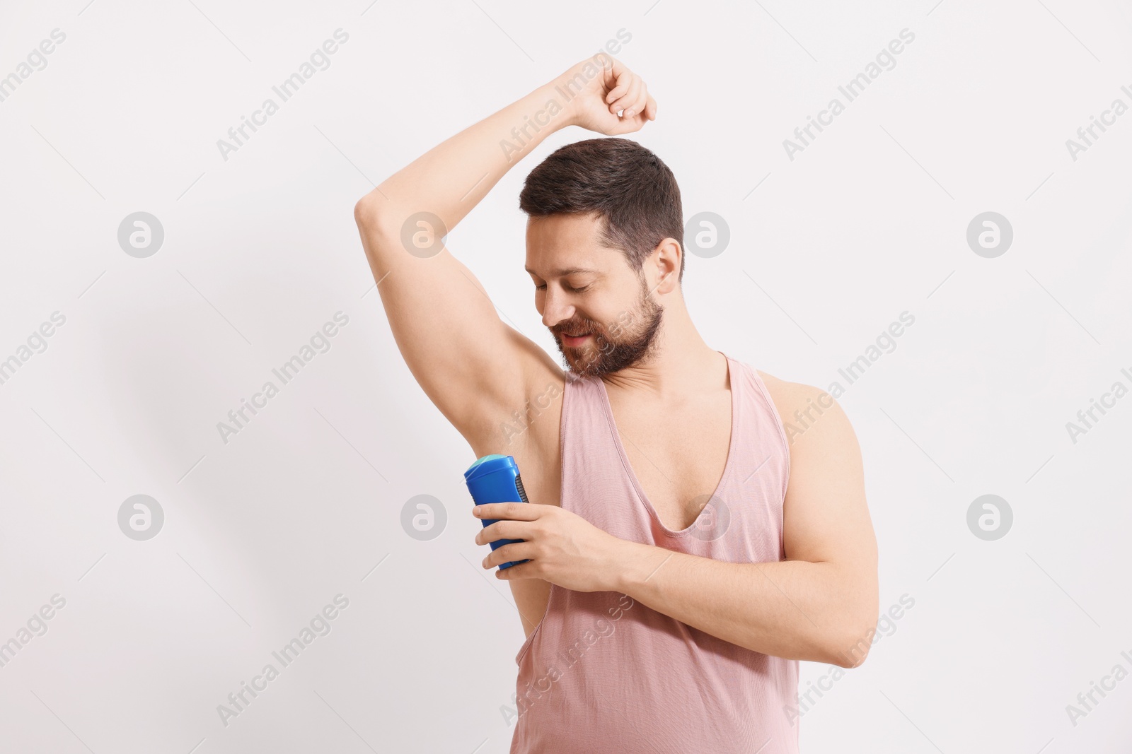 Photo of Man applying solid deodorant on white background