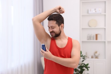 Smiling man applying roll-on deodorant at home