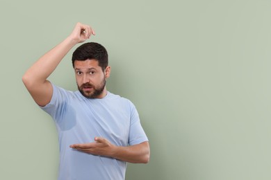 Emotional man before using deodorant on green background. Space for text