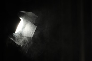 Photo of Professional spotlight and smoke in darkness. Space for text