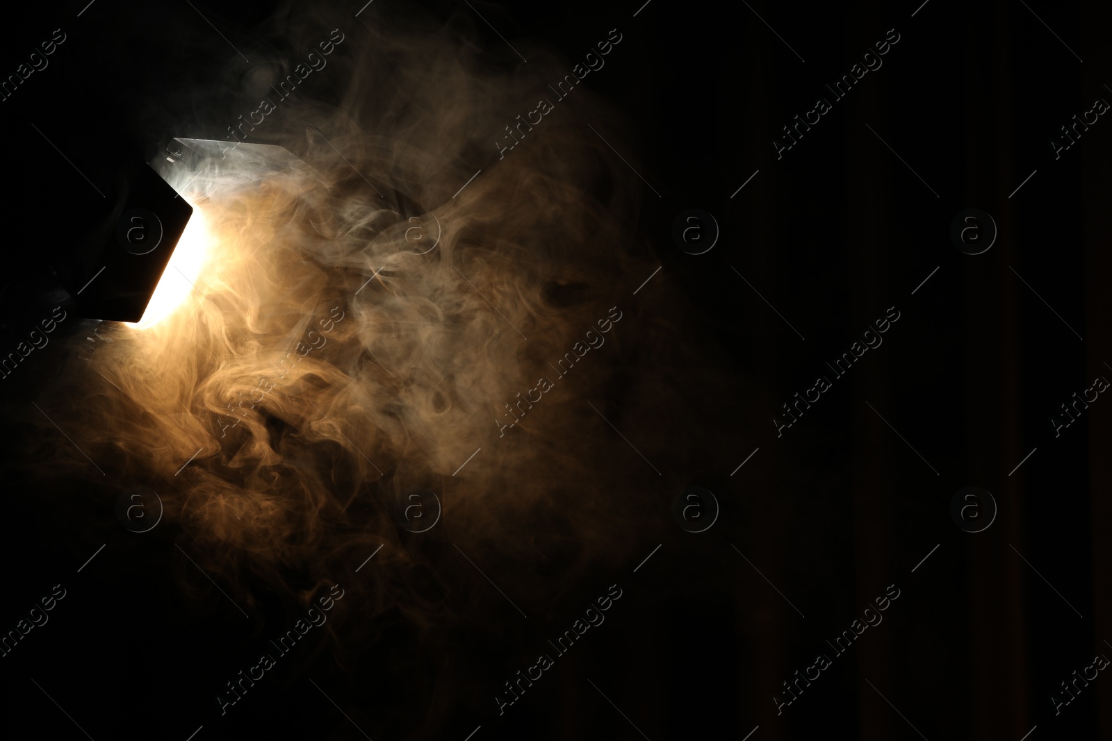 Photo of Professional spotlight and smoke in darkness. Space for text