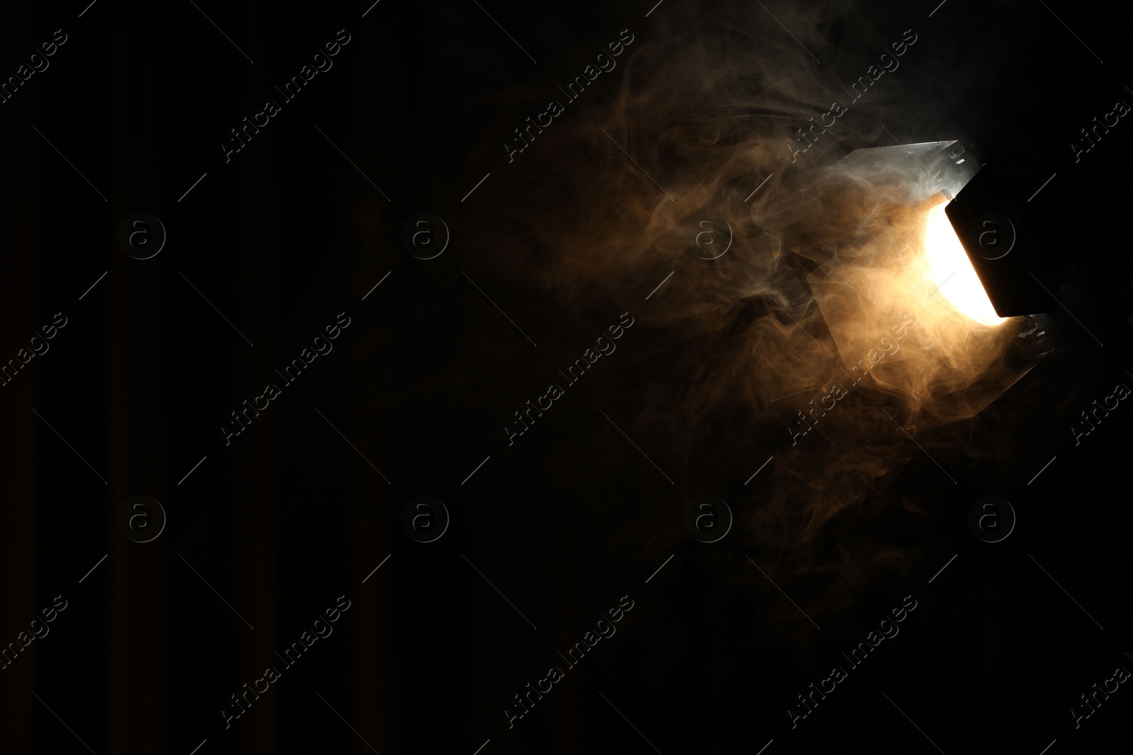 Photo of Professional spotlight and smoke in darkness. Space for text