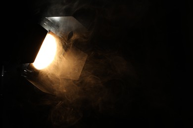 Photo of Professional spotlight and smoke in darkness. Space for text