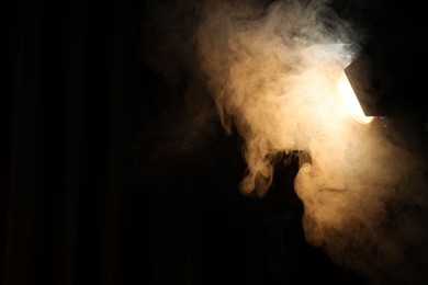 Photo of Professional spotlight and smoke in darkness. Space for text