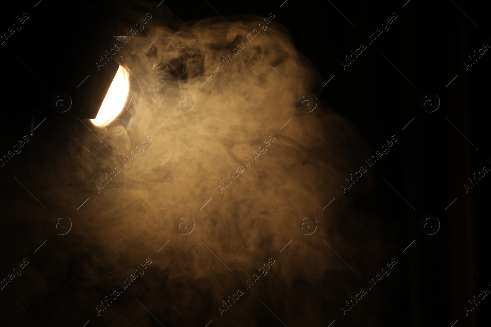 Photo of Professional spotlight and smoke in darkness. Space for text