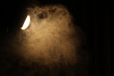 Photo of Professional spotlight and smoke in darkness. Space for text