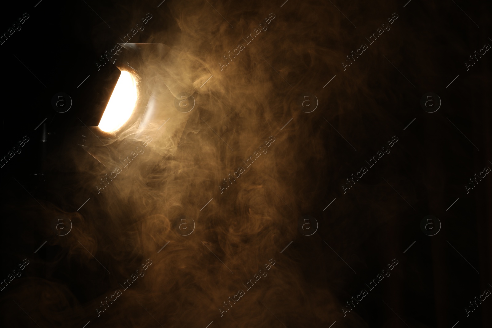 Photo of Professional spotlight and smoke in darkness. Space for text