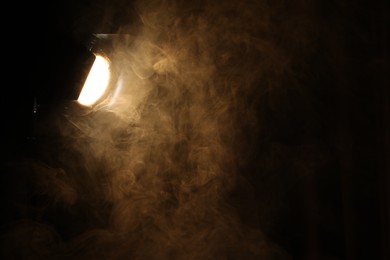 Photo of Professional spotlight and smoke in darkness. Space for text