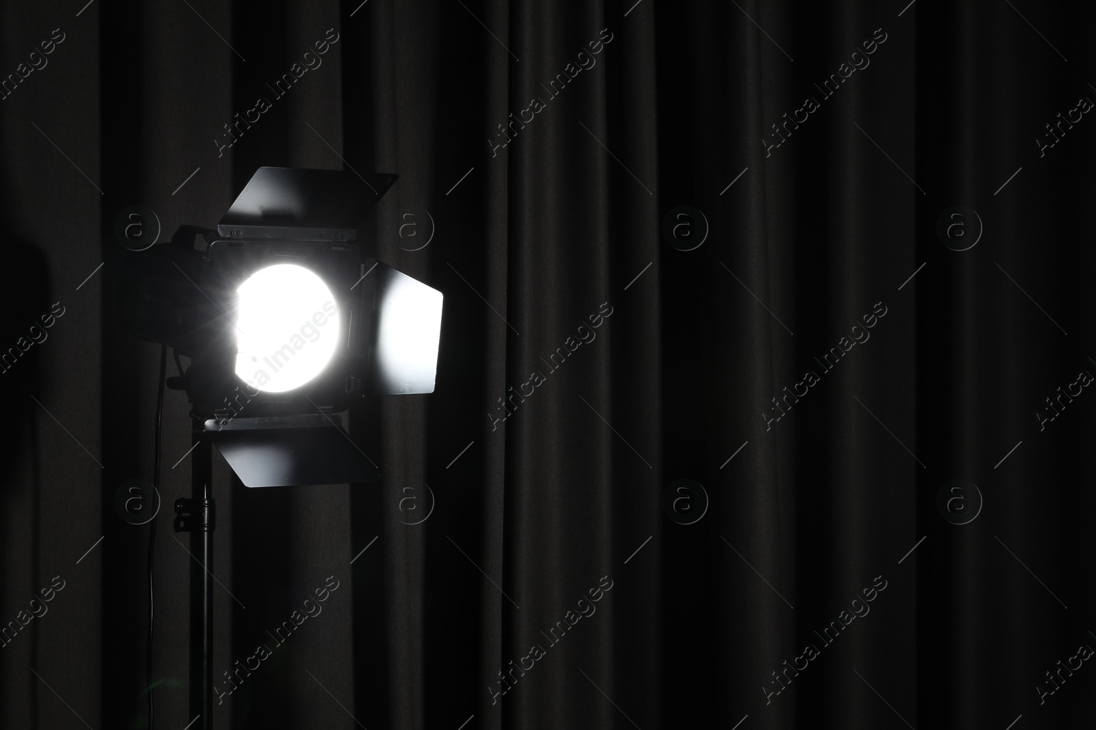 Photo of Professional spotlight against dark curtain. Space for text