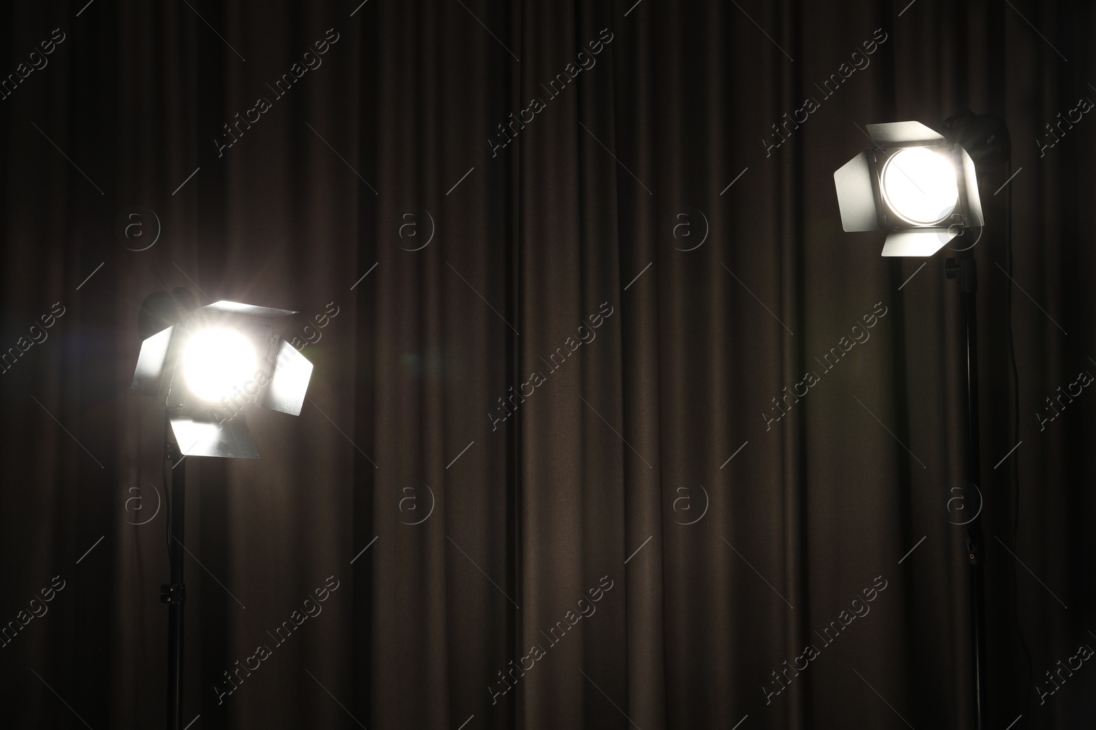 Photo of Two spotlights against curtain. Professional lighting equipment